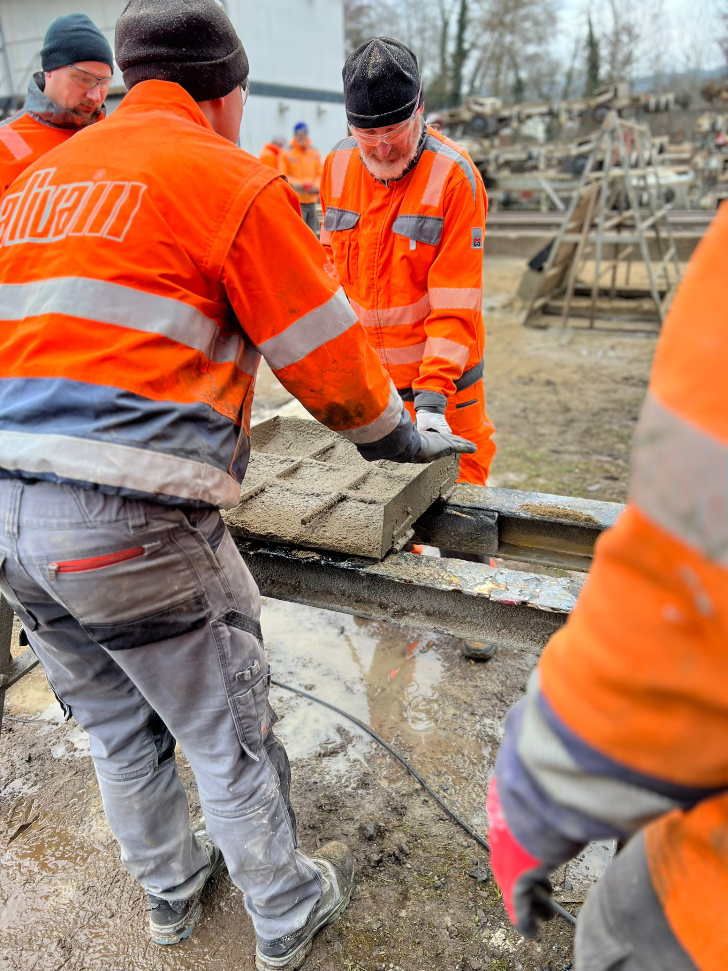Zwei Eitzen-Mitarbeiter in Warnkleidung bei der praktischen Arbeit mit einer Betonform auf der Baustelle